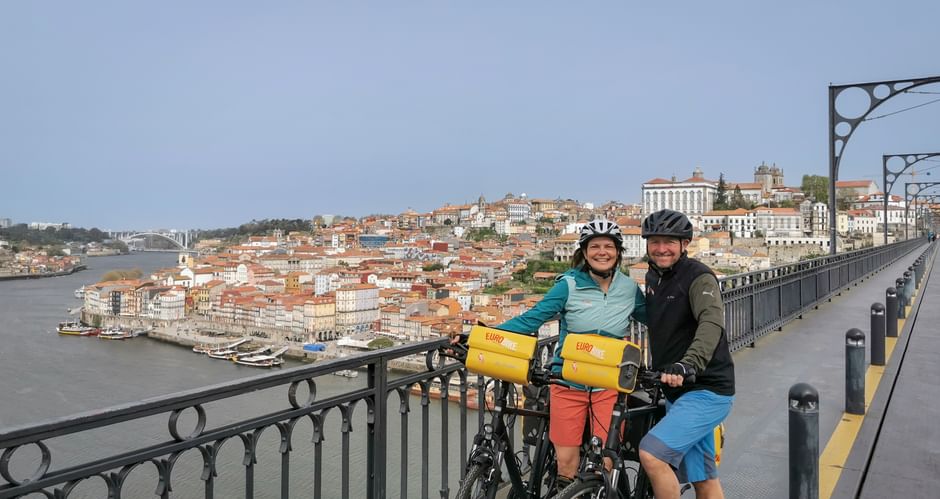 Happy couple cycling on the bridge in Porto