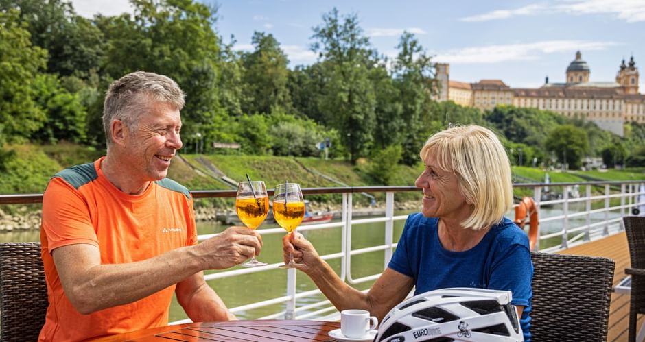 A couple with Aperol on the ship's terrace, Melk Abbey in the background