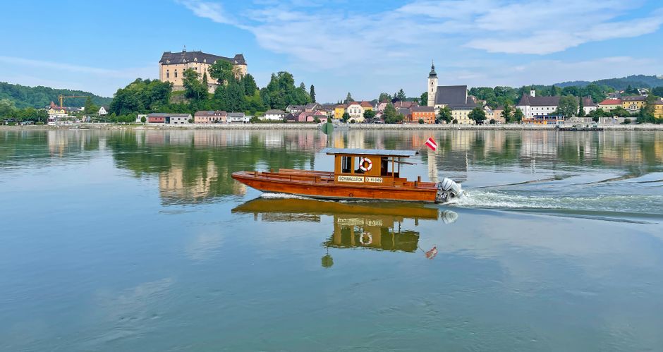Blick vom Donauufer aus auf Grein, mit einem kleinen Holzboot im Vordergrund