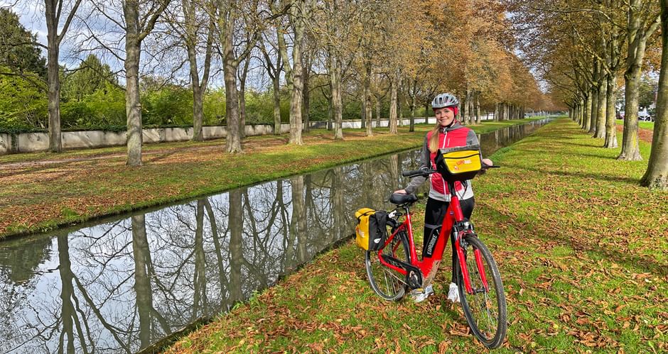 Cyclist in autumnal avenue on a small river