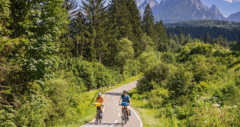 Zwei Radfahrer auf dem Radweg im Kanaltal bei Tarvis mit den Bergen im Hintergrund