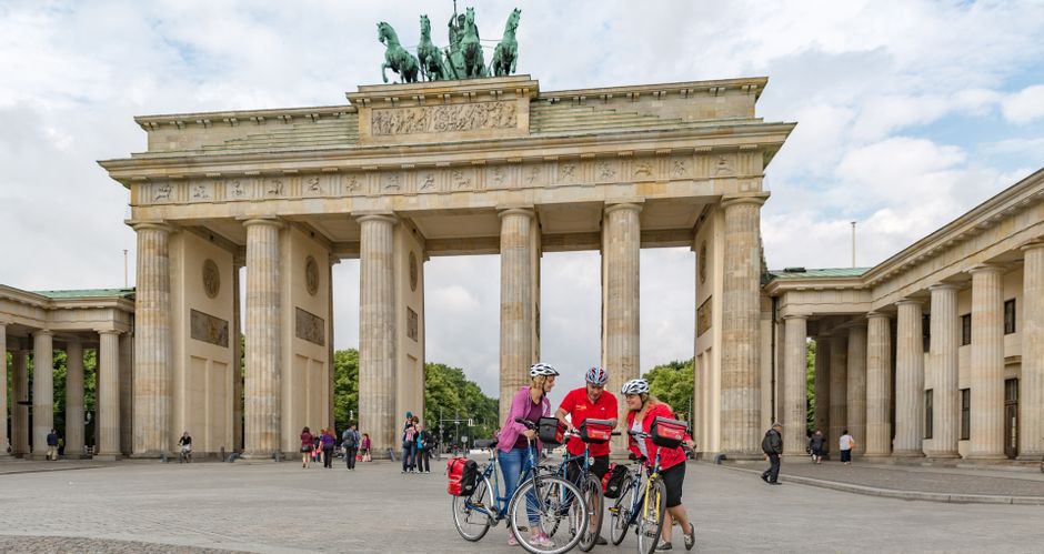 Drei Radfahrer vor dem Brandenburger Tor in Berlin
