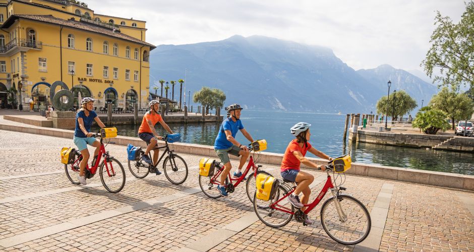 Group of cyclists in the centre of Riva del Garda with lake view
