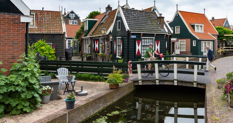 Radfahrer auf einer kleinen Brücke über einen Kanal im historischen Ort Volendam