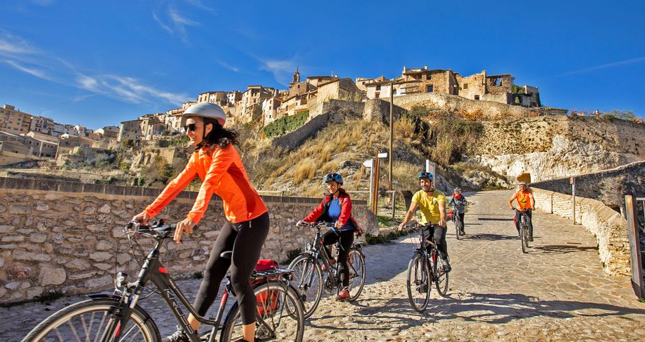 Ein historisches Dorf auf einem Berg gelegen, mit einer Gruppe von Radfahrern im Vordergrund