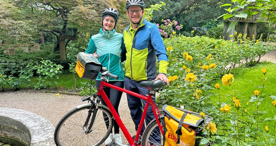 Cyclist and cyclist standing with bicycle in rose garden