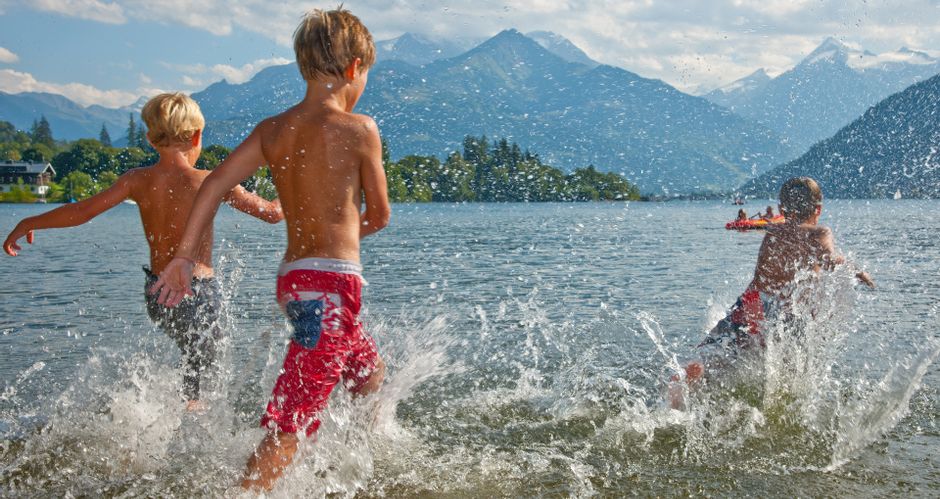 Drei Kinder spritzen im Wasser im Zeller See