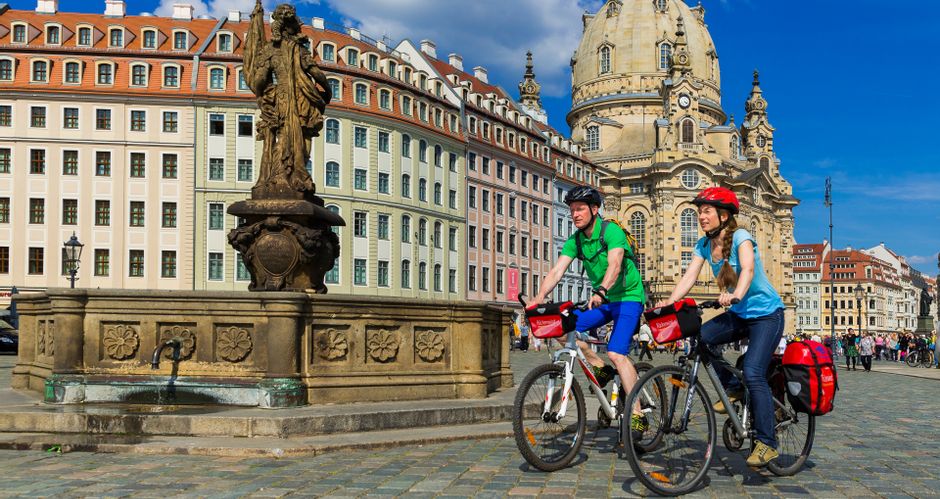 Two cyclists next to a fountain on the forecourt of the Frauenkirche in Dresden