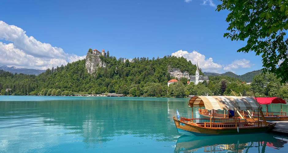 Bleder See mit Boot und Burg im Hintergrund