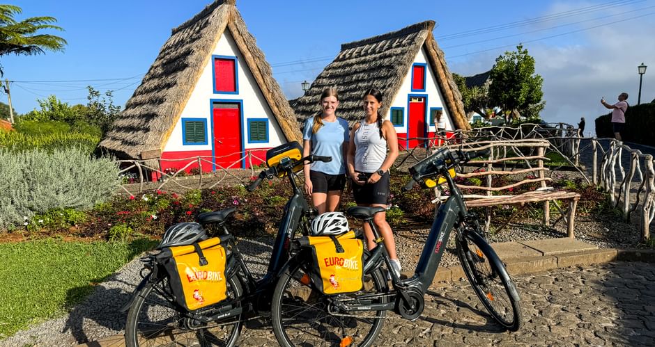 Two cyclists in front of the famous straw houses in Santana